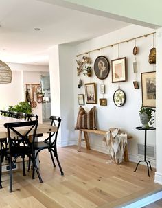 a dining room table with chairs and pictures on the wall behind it, along with other decorations