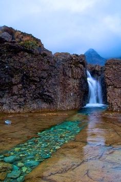 there is a small waterfall coming out of the rocks