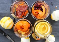 four glass jars filled with different types of fruit and vegetables next to an apple slice