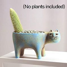 a ceramic cat planter sitting on top of a white shelf next to a cactus