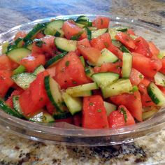 a glass bowl filled with cucumber and green peppers on top of a table