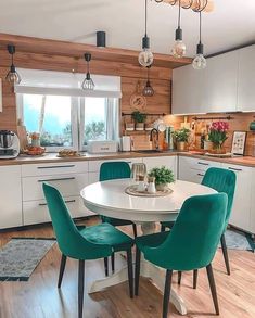 a white table with green chairs in a kitchen next to a sink and stove top oven