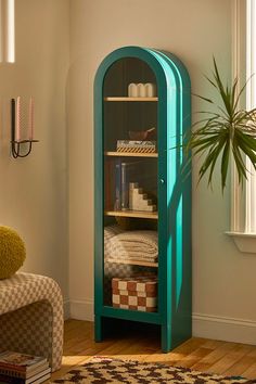 a room with a green shelf in the corner and a potted plant next to it