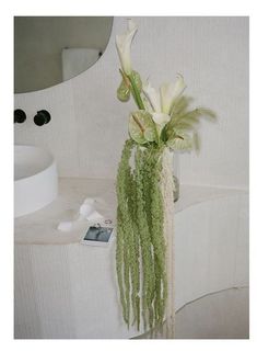 a vase filled with white flowers sitting on top of a table next to a mirror