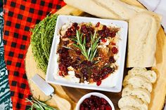 a platter with bread, cranberry sauce and crackers next to it