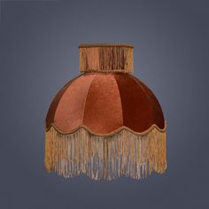 a lamp shade with tassels hanging from it's sides on a gray background