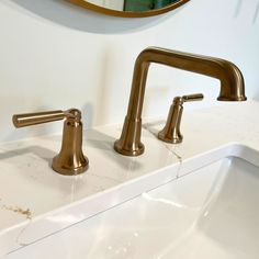 two gold faucets on a white sink in a bathroom