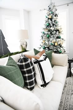 a living room with a christmas tree in the corner and pillows on the couches