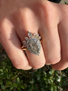 a woman's hand with a ring on top of her finger and an oval shaped diamond in the middle