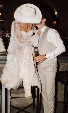 a man in a white suit and hat kissing a woman wearing a white wedding dress