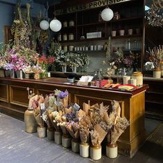 a bunch of flowers that are sitting on a counter in a room with lights and vases