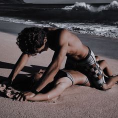 a man in swimsuit laying on the beach next to the ocean with his head down