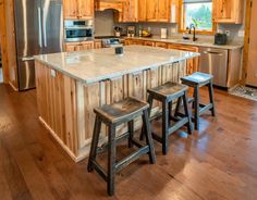 a kitchen with two stools next to an island in the middle of the room