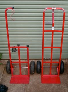 two red hand trucks sitting next to each other in front of a garage door on wheels