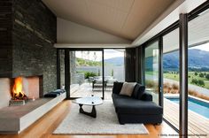 modern living room with fireplace and large glass doors leading to outdoor deck area that overlooks the mountains