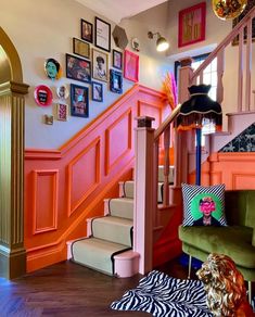 a living room filled with furniture and pictures on the wall next to a stair case