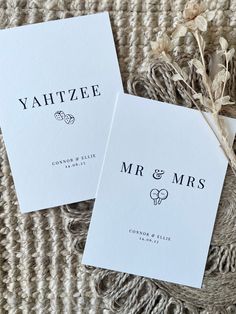 two white cards with black lettering on them sitting next to some dried flowers and twine