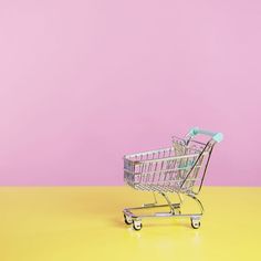 an empty shopping cart on a yellow and pink background with space for text or image