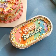 a birthday cake sitting on top of a table next to a box with the word happy birthday written on it