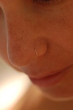 a close up of a woman's nose with a piercing in the middle of her nose