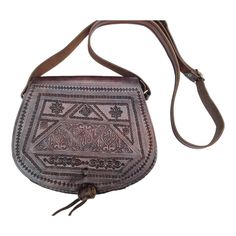 Small Moroccan leather crossbody bag in dark brown. This boho sling bag has been handmade from genuine leather and features a tooled pattern and multiple inside pockets. The shoulder strap is adjustable. This hippie bag is ideal for every day, travelling, festivals and going out. 100% real leather. width: 25cm = 10" height: 21cm = 8.5" shoulder strap adjustable Great vintage condition Check out my other items! I offer FREE SHIPPING on any addition items.  For my vintage Moroccan leather bags, ch Brown Artisan Saddle Shoulder Bag, Traditional Brown Leather Shoulder Bag, Traditional Brown Satchel Saddle Bag, Traditional Brown Crossbody Satchel, Traditional Brown Leather Saddle Bag, Traditional Brown Soft Leather Bag, Traditional Brown Bag With Leather Lining, Traditional Brown Crossbody Shoulder Bag, Brown Hand Tooled Shoulder Bag For Travel