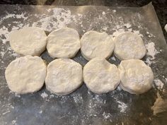 eight uncooked pizza doughs on a baking sheet