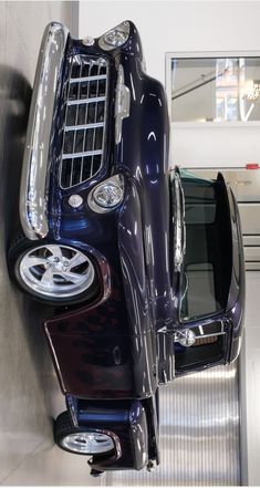 the front end of a purple car parked in a garage next to a wall with mirrors on it