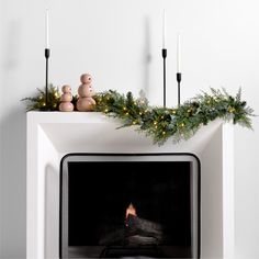 a fireplace with candles and christmas decorations on it