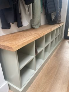 a coat rack with several coats hanging on the wall next to it, and some shoes