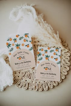 wedding stationery with oranges and greenery on the front, two cards are laying on a doily