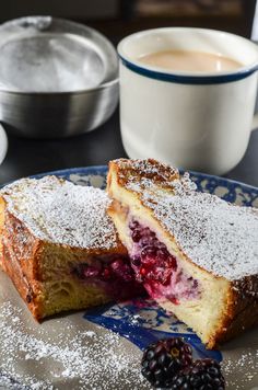 two pieces of cake with powdered sugar on top and berries in the foreground