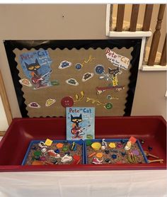 a red tray filled with lots of toys on top of a white cloth covered table