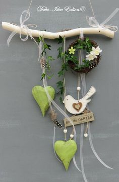 a clock with green hearts hanging from it's sides on a wall next to flowers