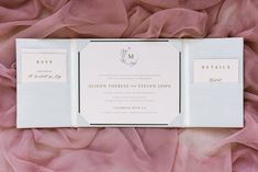 the wedding stationery is laid out on a bed of pink fabric