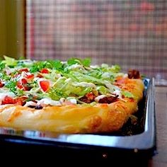 a pizza sitting on top of a pan covered in cheese and lettuce toppings