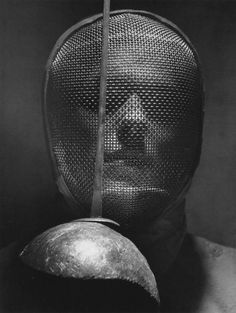 a black and white photo of a person wearing a helmet with a metal face covering