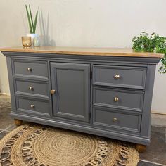 a large gray dresser sitting on top of a rug next to a potted plant