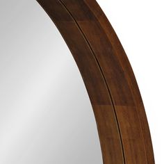 an oval mirror is shown against a white wall and has wood trim around the edge