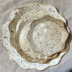 three white plates stacked on top of each other with black speckles in them