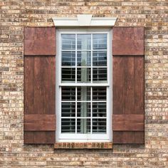 an open window with wooden shutters on a brick wall