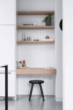 a white room with some shelves and a stool in the corner next to it,