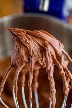 a close up of a metal whisk with chocolate frosting