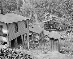 an old black and white photo of some houses in the woods with trees around them