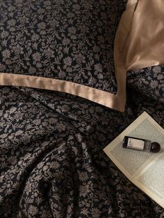 an open book on top of a bed next to a pillow