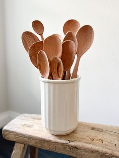 several wooden spoons in a white cup on a table