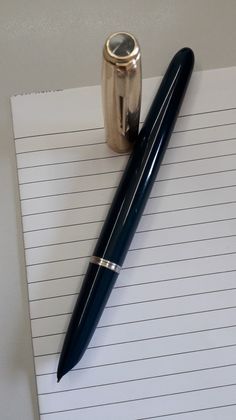 a pen sitting on top of a piece of lined paper next to a coffee mug