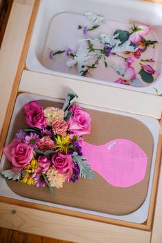 flowers are placed on the table next to a tray with a pink whale painted on it