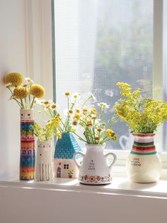 three vases filled with yellow flowers sitting on a window sill next to each other