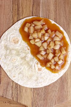 an uncooked tortilla covered in caramel sauce and chopped apples on top