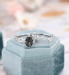 a silver ring with a black diamond in it sitting on a blue velvet gift box